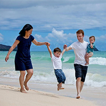 Honolulu Family Photography - Family walking on Honolulu Beach swinging the son, having a Great time.