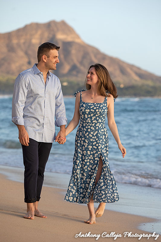 Jesse and Ariella holding hands walking on Waikiki Beach, with Diamond Head as a backdrop