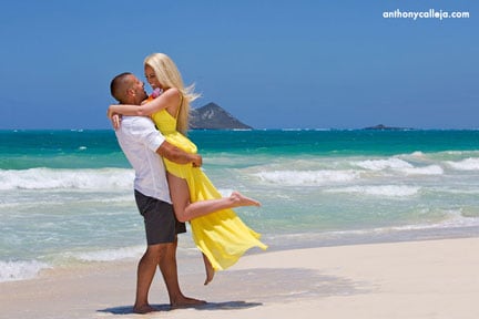 Engagement Photography of a couple at Waimanalo Beach. He lifts her in the air as they smile at each other